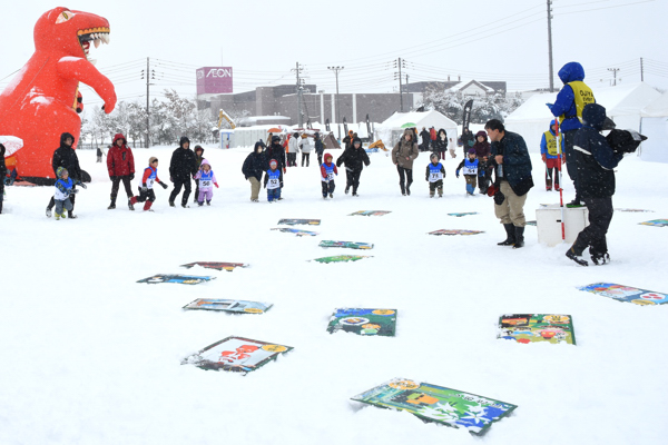 ジャンボ絵札が並べられた雪原と参加者の画像