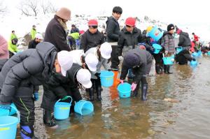 おおぜいの小学生が河川敷で放流している画像