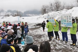 サケの一生についての説明を真剣に聞いている小学生の画像