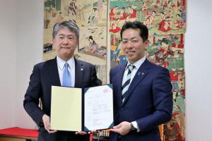 目録をもって記念撮影をする敦井代表取締役と宮崎市長の画像