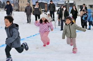 雪の上を笑顔で走る子どもたちの画像