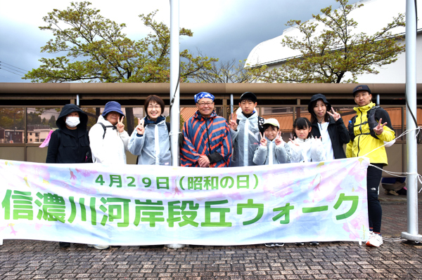 信濃川河岸段丘ウォークの横断幕と記念撮影をする参加者の画像