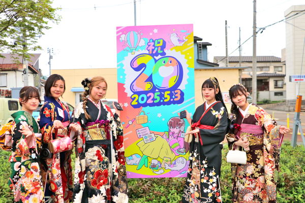 POPinおぢやの看板の前で記念撮影をする二十歳を祝う会の出席者の画像