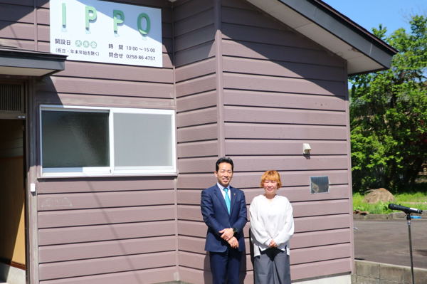 施設の看板の下でフォルトネット小千谷の柳田代表と並ぶ宮崎市長の画像