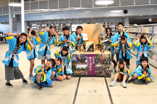 絵本と記念撮影をする東山小学校の全校児童の画像