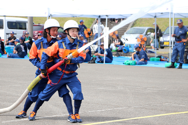小型ポンプで放水を行う2人の消防団員の画像