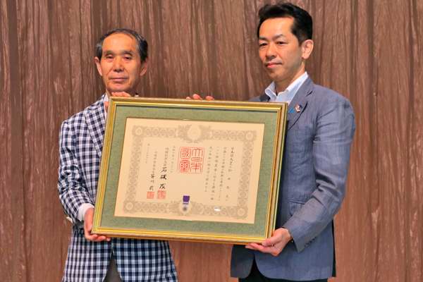 紺綬褒章を持つ宮崎市長と松井さんの画像