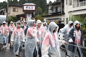 雨の中、雨合羽を着て屋台を引く42歳同級会のみなさんの画像