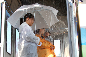 降雨体験車で強い雨を体験する市民の画像